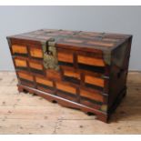 A KOREAN PERSIMMON WOOD TRUNK WITH SYMETRICAL VENEERS, BRASS MOUNTS AND LOCK PLATE, WITH DEALERS