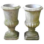 A PAIR OF DECORATIVE 'STONE' URNS, 20TH CENTURY, campagna form with fluted waists, raised on square