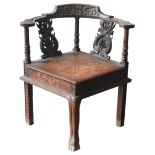A CARVED OAK CORNER CHAIR, 19TH CENTURY, the bowed top rail carved with a grotesque amongst