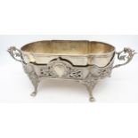 A SILVER PLATED CONTINENTAL TABLE CENTRE ON FOUR FOLIATE FEET, SCROLLED SIDE HANDLES AND LIFT OUT