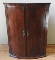 AN OAK BOW FRONT CORNER CUPBOARD, 19TH CENTURY, gadroon and dentil cornice above two cupboard