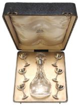 A GEORGE V SILVER MOUNTED GLASS LIQUER DECANTER AND A SET OF SIX SILVER GOBLETS, in presentation