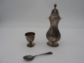 A SILVER SUGAR SIFTER AND A BOXED EGGCUP WITH SPOON, the sifter of fluted waisted form with finial