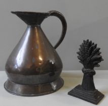 A GEORGIAN CAST-IRON DOORSTOP AND COPPER MEASURING JUG, the doorstop modelled as a sheaf of wheat,