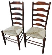 A PAIR OF PINE LADDER BACK CHAIRS, 20TH CENTURY, with rush covered seat panels, raised on turned