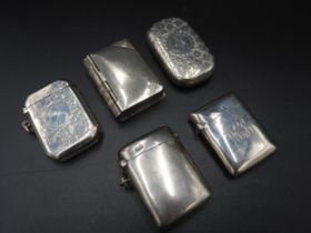 FOUR SILVER VESTA CASES AND  A WHITE METAL VESTA, the lot comprised of: a scroll foliate chased
