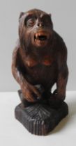 A VINTAGE BLACK FOREST CARVING OF A MONKEY, naturalistically carved clutching a branch and bearing