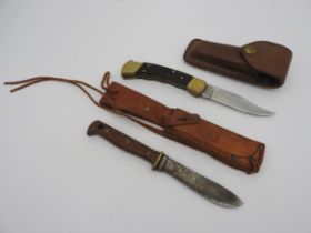 A VINTAGE PUMA KNIFE WITH EMBOSSED SHEATH and marked Germany DBGM and a Buck 110 folding knife in