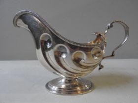 A LATE VICTORIAN SILVER SAUCEBOAT, elegantly embossed in a scrolling shell form with gadrooned