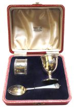 A SILVER CORONATION EGGCUP, SPOON AND NAPKIN RING IN PRESENTATION BOX, decorated in low relief