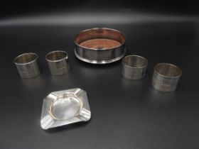 A SILVER BOTTLE COASTER, ASHTRAY AND FOUR NAPKIN RINGS, the coaster marked London, 1989 (12.5 cm