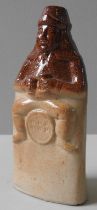 AN OLDFIELDS POTTERY SALT GLAZED FLASK, CIRCA 1840, modelled as 'Old Tom', holding a jug and