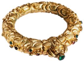 A NINETEENTH CENTURY INDIAN GILT BANGLE, CIRCA 1880 the heavily chased hinged bangle with stylised