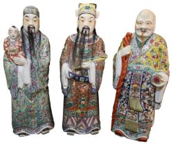 AN IMPRESSIVE SET OF THREE FAMILLE ROSE FIGURES SHOWN STANDING IN TRADITIONAL ROBES (3), 57cm