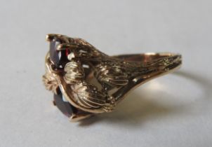 AN UNUSUAL GARNET MOUNTED GOLD RING, the two pear shaped garnets set in a foliate decorated mount,