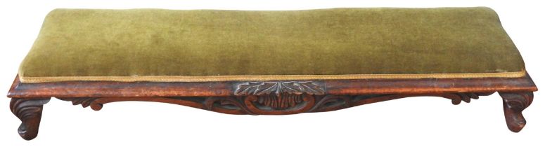 A VICTORIAN MAHOGANY LONG FOOT STOOL, the overstuffed panel raised on a scroll foliate carved frame,