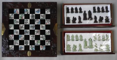 A CHINESE DECORATED CHESS BOARD AND PIECES, the folding board with decorated panels, dragon carved