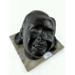 A slightly terrifying bronze effect painted plaster face of a child. H20cm