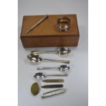 Small wooden box with collection of silver items, including a napkin ring, spoons, rotating pencil,