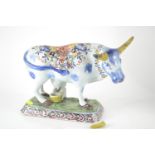 A Dutch Delft pottery figure of a cow and milkmaid, decorated in polychrome enamels, shaped base, 17