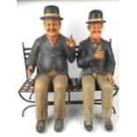 Stan Laurel and Oliver Hardy resin models sat on a metal  garden bench