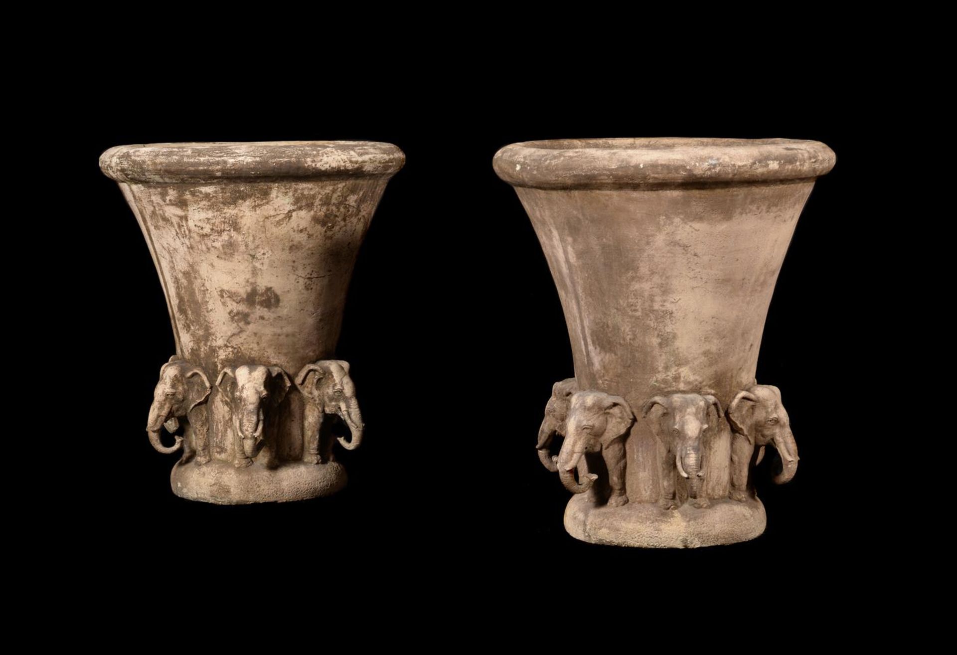 A PAIR OF COMPOSITION STONE URNS WITH ELEPHANT TERMINALS, PROBABLY 20TH CENTURY