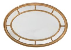 AN OVAL GILTWOOD AND COMPOSITION WALL MIRROR IN VICTORIAN STYLE