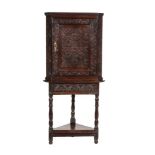 A CARVED OAK CORNER CABINET ON STAND