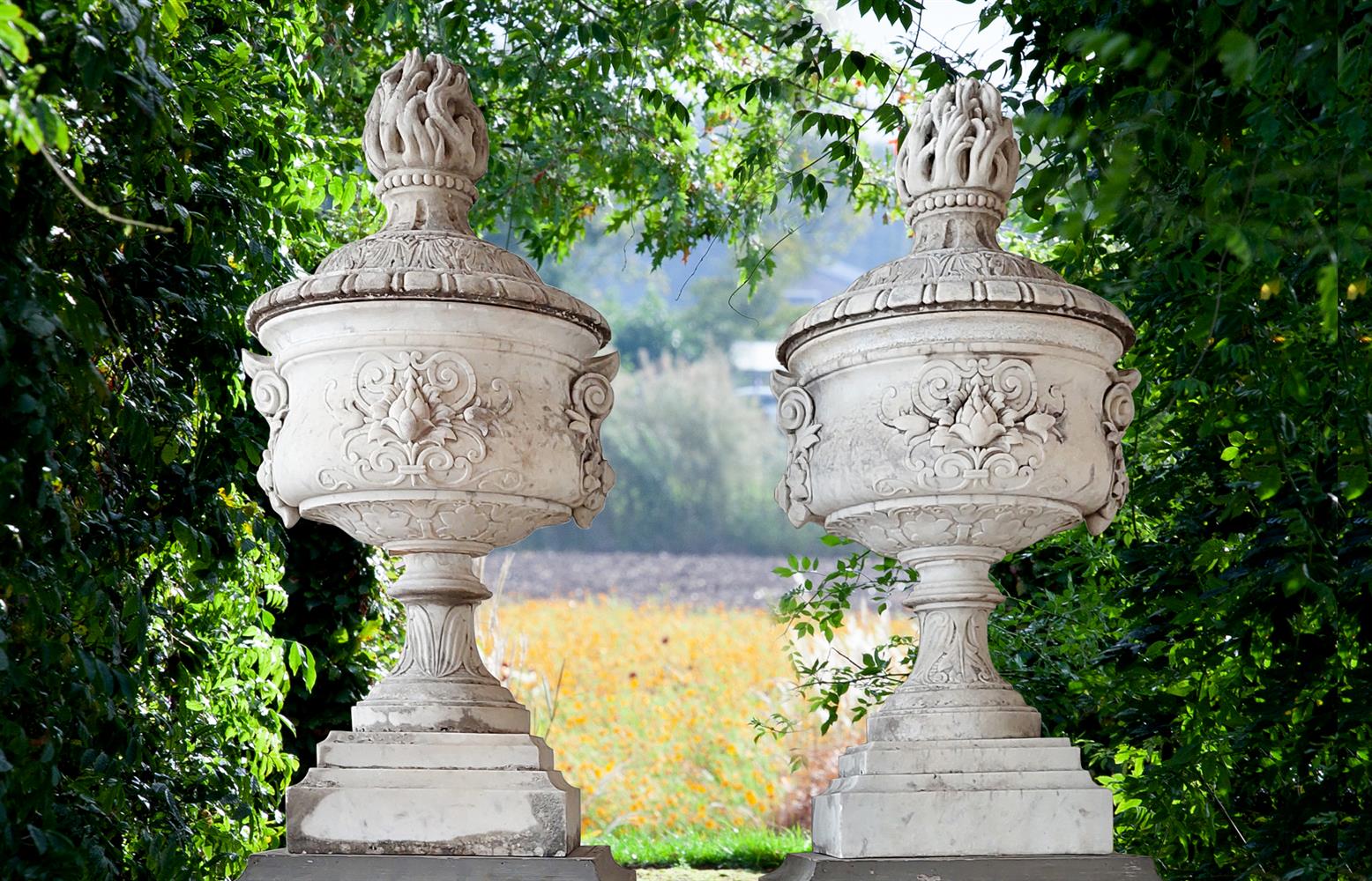 ‡ A PAIR OF ORNATELY CARVED WHITE MARBLE URNS AND COVERS