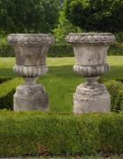 ‡ A PAIR OF CARVED LIMESTONE GARDEN URNS IN 18TH CENTURY STYLE
