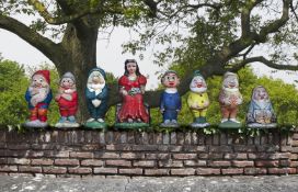 Ω AFTER WALT DISNEY, A POLYCHROME PAINTED COMPOSITION STONE GROUP OF SNOW WHITE AND THE SEVEN DWARFS