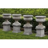 Ω A SET OF FOUR CARVED LIMESTONE GARDEN URNS