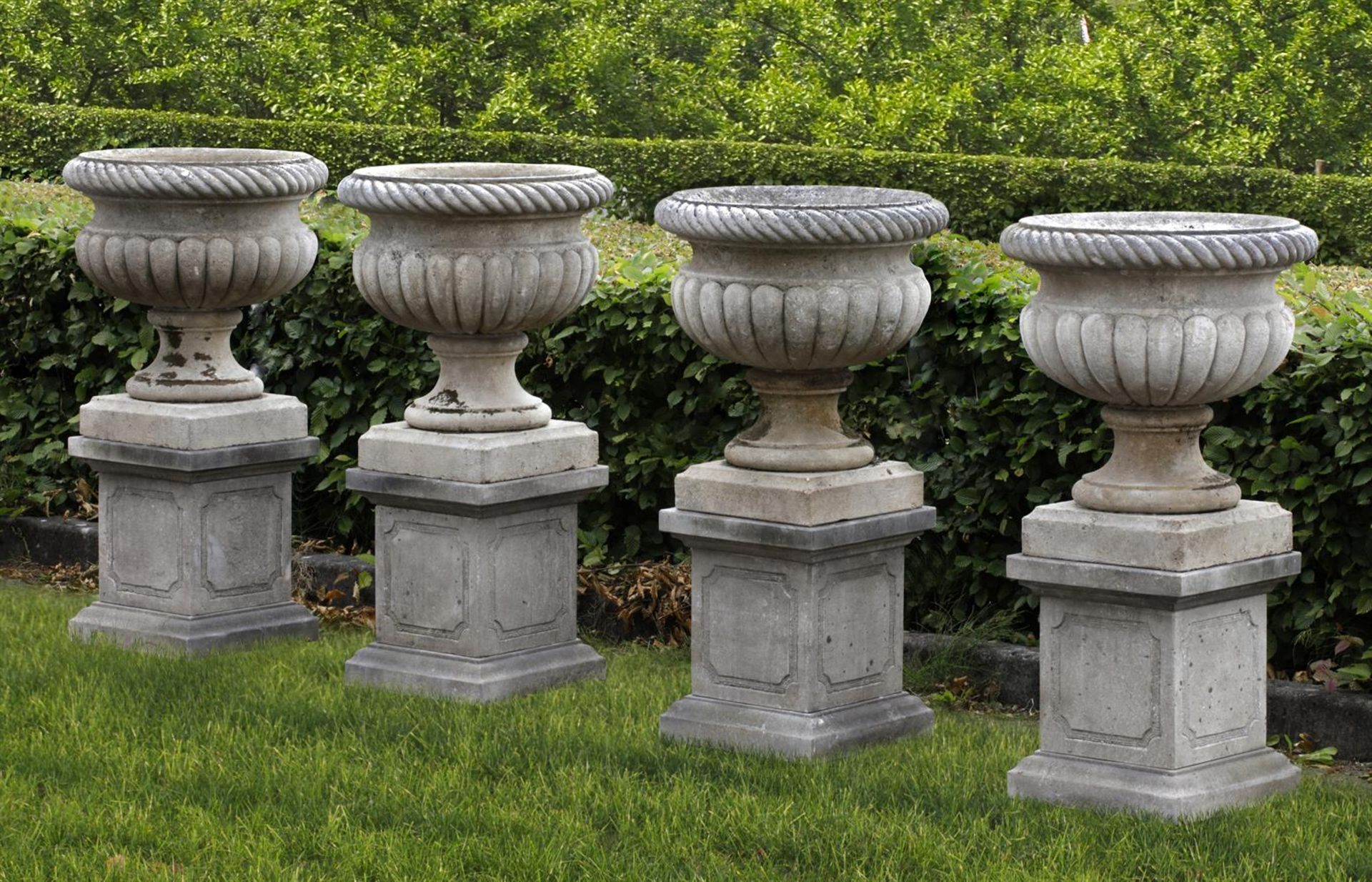 Ω A SET OF FOUR CARVED LIMESTONE GARDEN URNS