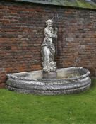 Ω A COMPOSITE STONE AND WROUGHT IRON MOUNTED WALL FOUNTAIN