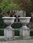 Ω A PAIR OF CARVED LIMESTONE URNS ON PEDESTALS