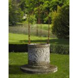 Ω A CONTINENTAL SCULPTED LIMESTONE AND WROUGHT IRON MOUNTED WELLHEAD