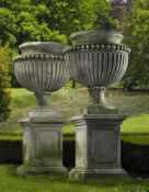 Ω A PAIR OF LARGE AND IMPRESSIVE CARVED LIMESTONE GARDEN URNS ON PLINTHS IN IMPERIO TASTE