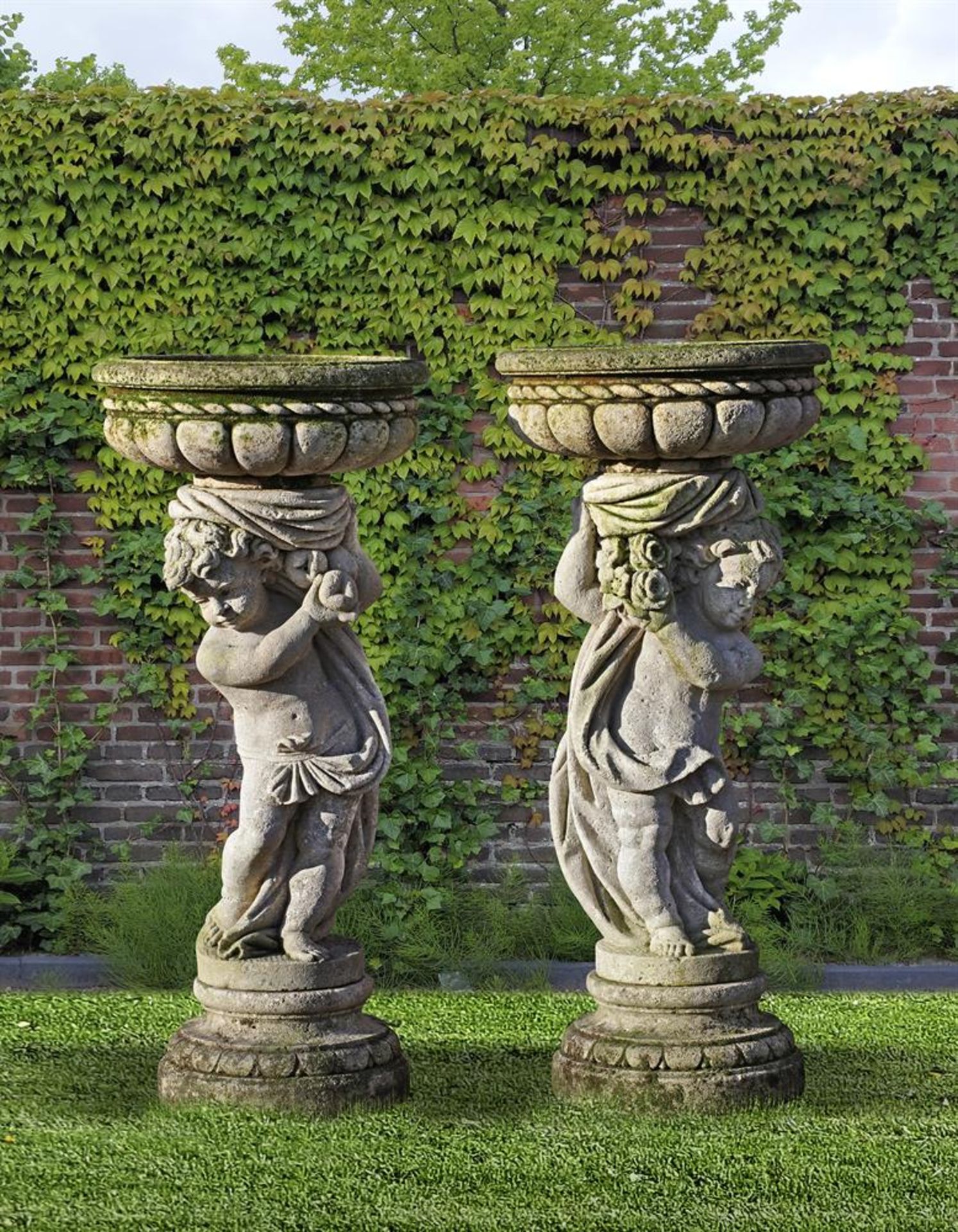 ‡ A PAIR OF SCULPTED LIMESTONE PEDESTAL PLANTERS