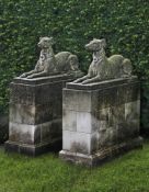 Ω A PAIR OF SCULPTED LIMESTONE MODELS OF RECUMBENT HOUNDS