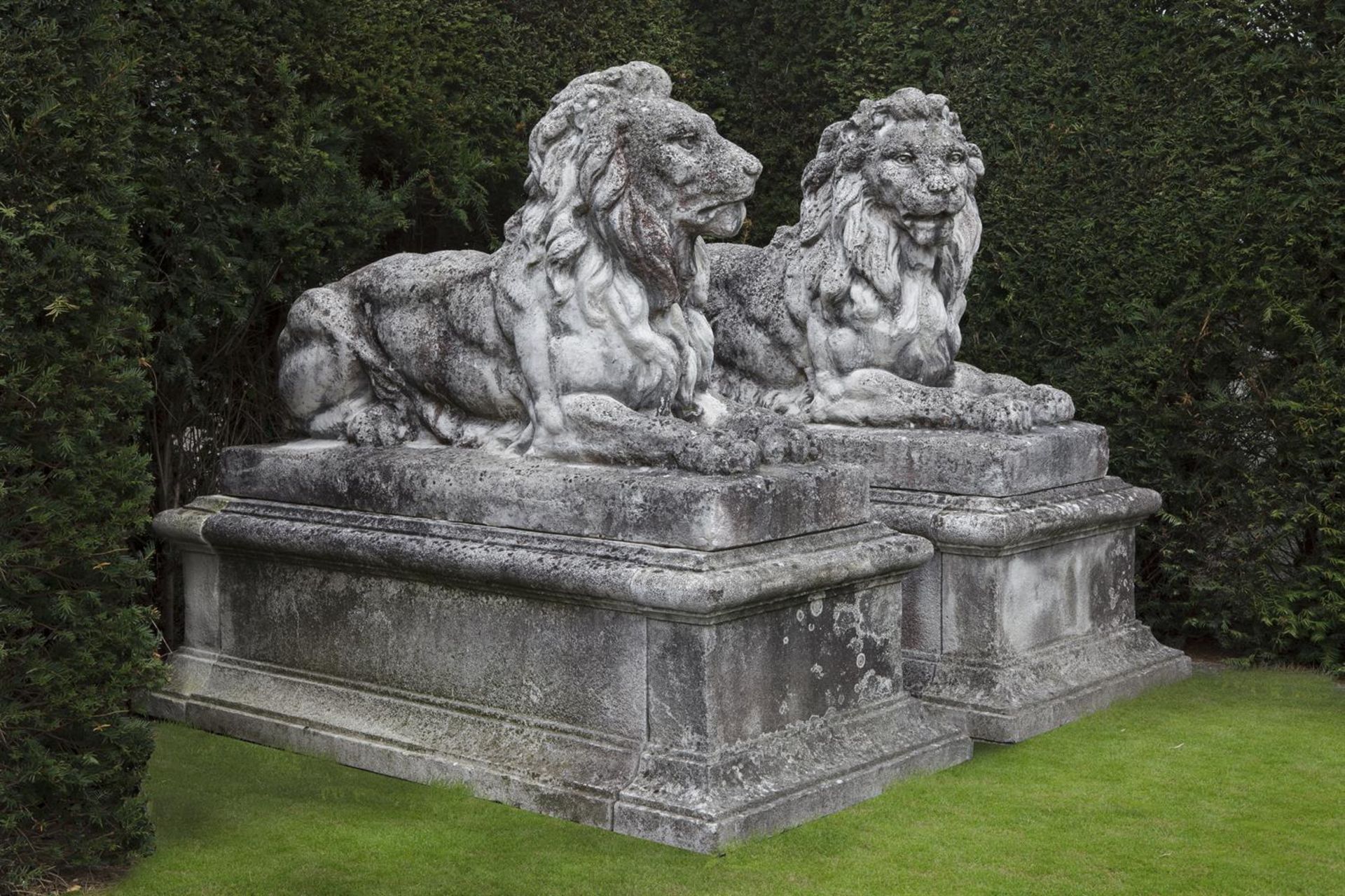 Ω A PAIR OF SUBSTANTIAL AND IMPRESSIVE STONE COMPOSITION GARDEN MODELS OF RECUMBENT LIONS