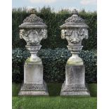 Ω A PAIR OF COMPOSITION STONE GARDEN URNS ON PLINTHS