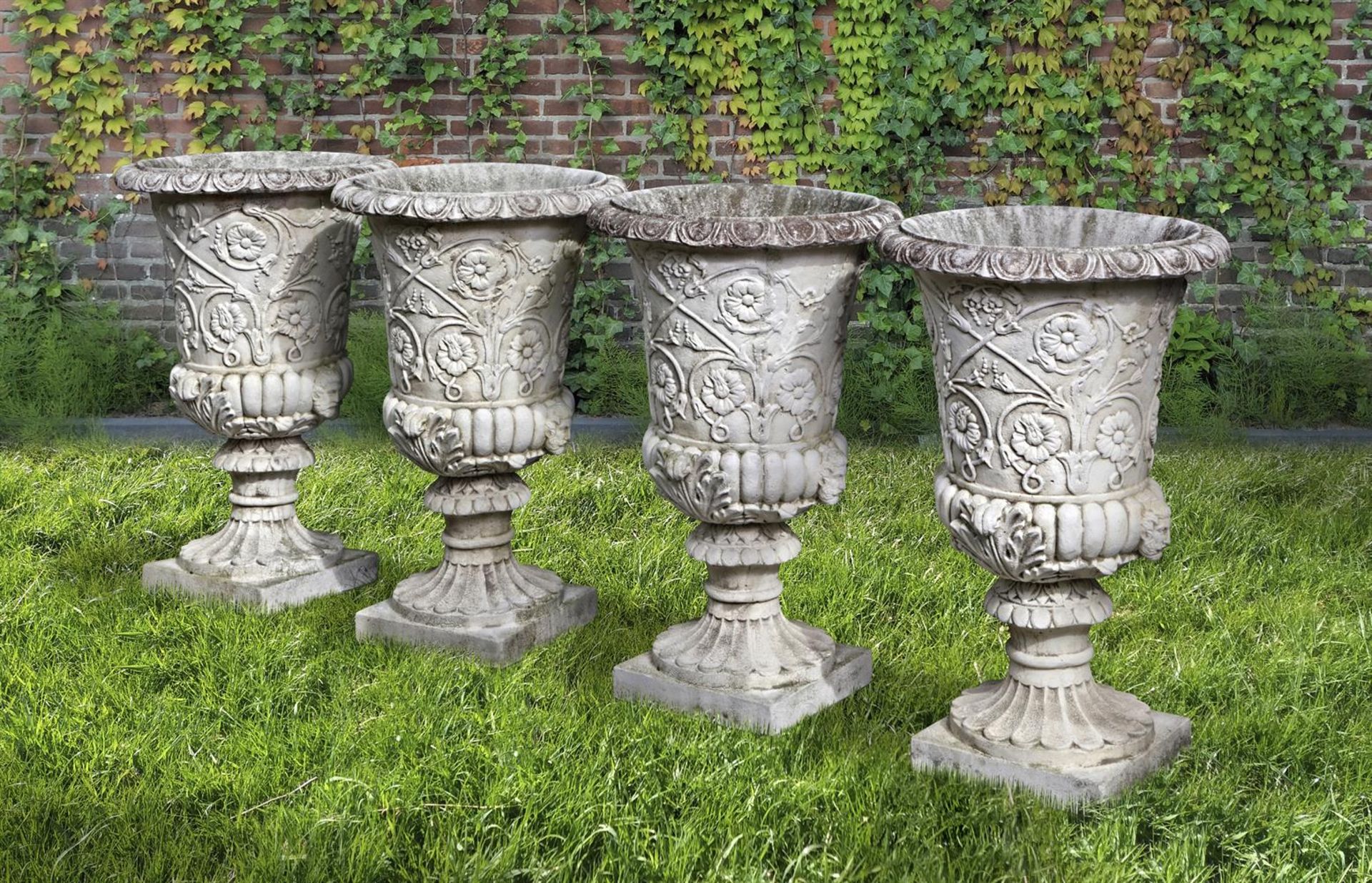 Ω A SET OF FOUR WHITE COMPOSITION STONE GARDEN URNS IN THE ROMANTIC CLASSICAL MANNER