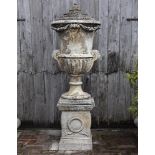 Ω A COMPOSITION STONE LIDDED URN ON PEDESTAL