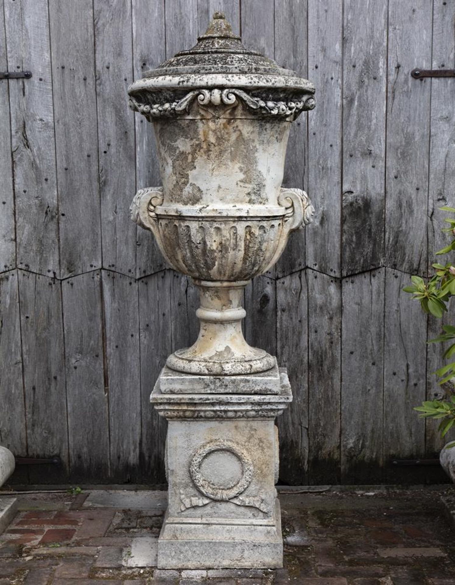 Ω A COMPOSITION STONE LIDDED URN ON PEDESTAL