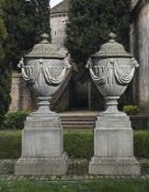 Ω A PAIR OF SUBSTANTIAL AND IMPRESSED CARVED LIMESTONE GARDEN URNS ON PLINTHS