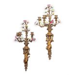 A PAIR OF GILT METAL AND PORCELAIN MOUNTED THREE BRANCH WALL APPLIQUES