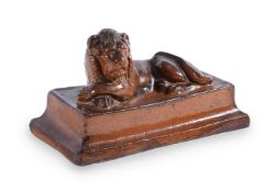 A SALT GLAZED STONEWARE MODEL OF A RECUMBENT LION ON A STEPPED BASE
