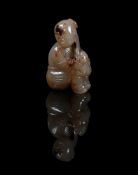 A Chinese celadon and brown jade carving of a boy and lion cub