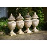 A SET OF FOUR WHITE PAINTED TERRACOTTA GARDEN URNS AND COVERS