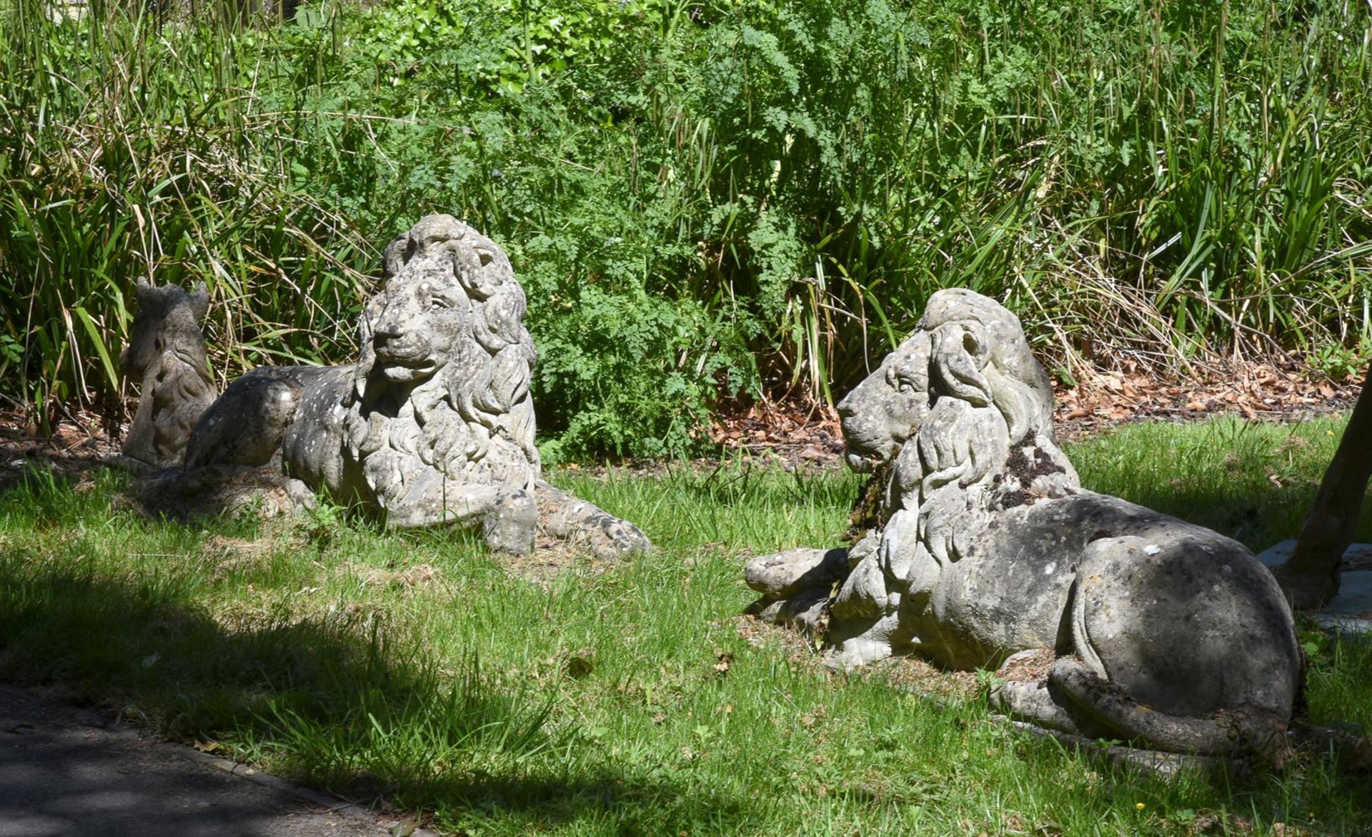 A PAIR OF COMPOSITION STONE MODELS OF RECUMBENT LIONS, AFTER CANOVA, 20TH CENTURY